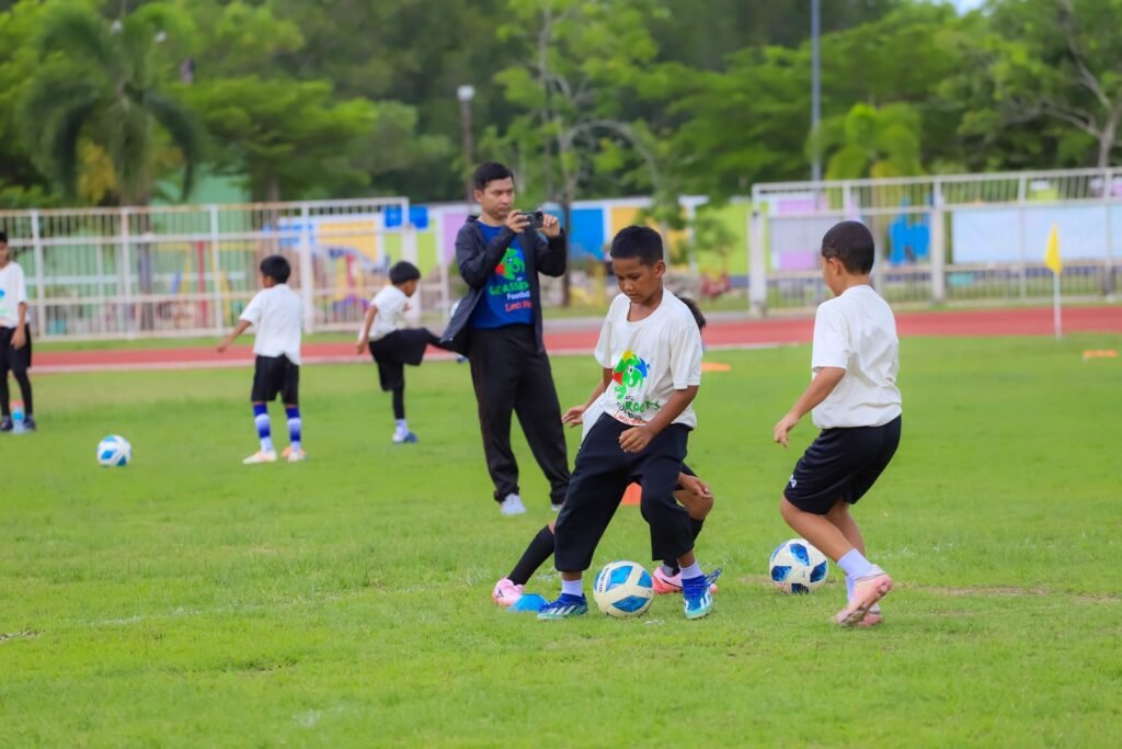 เยาวชนและผู้บริหารร่วมถ่ายภาพในกิจกรรม AFC Grassroots Football Day 2026 ที่สนามกีฬาฟุตบอล รัชกิจประการ จังหวัดสตูล